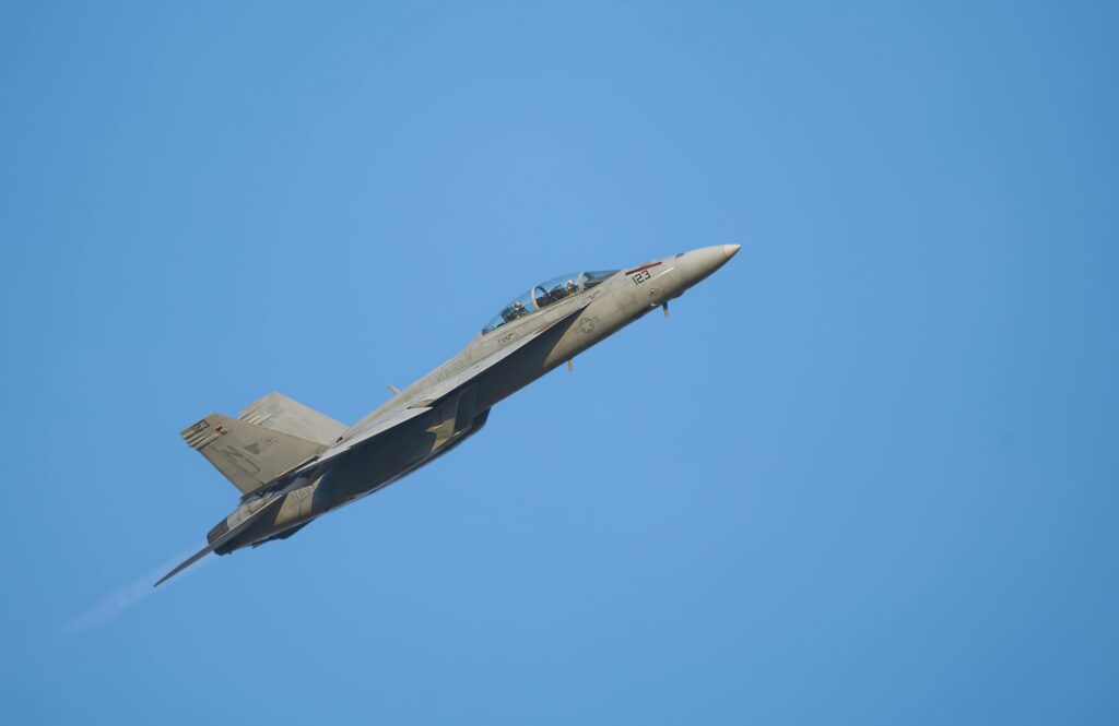 A military fighter jet ascending against a clear blue sky, showcasing power and precision.