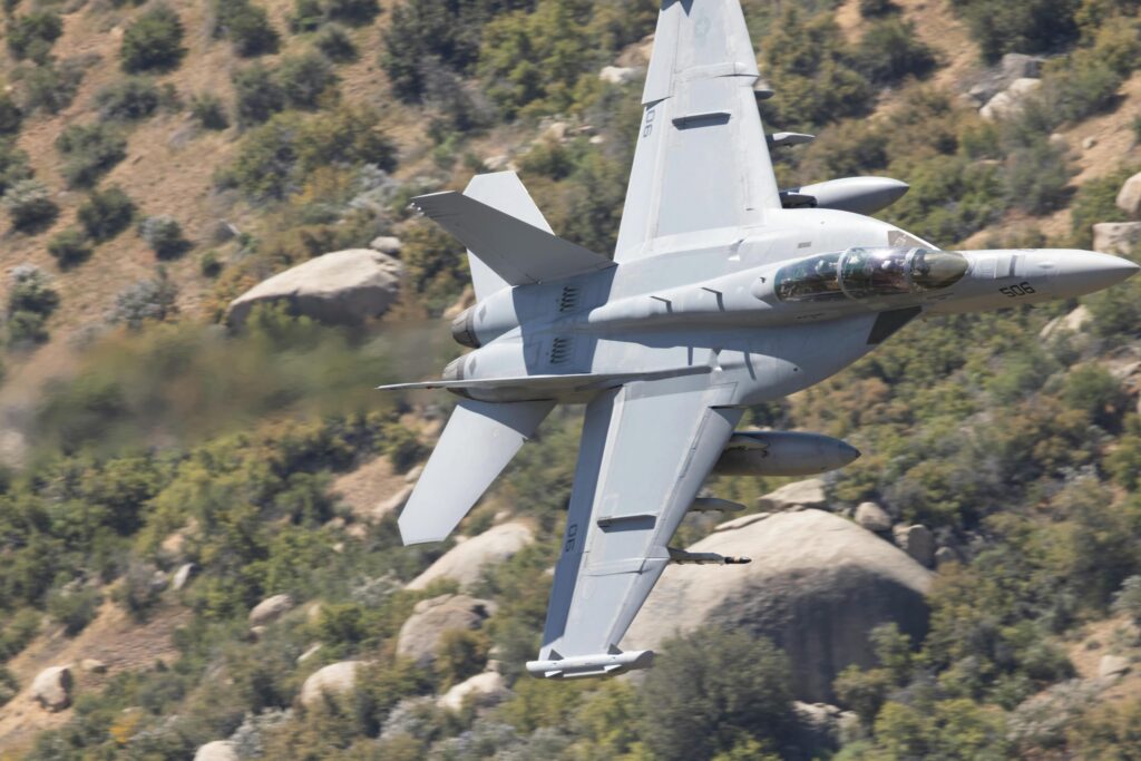 F-18 Super Hornet flies low over Kernville, California, showcasing speed and agility amidst rugged terrain.