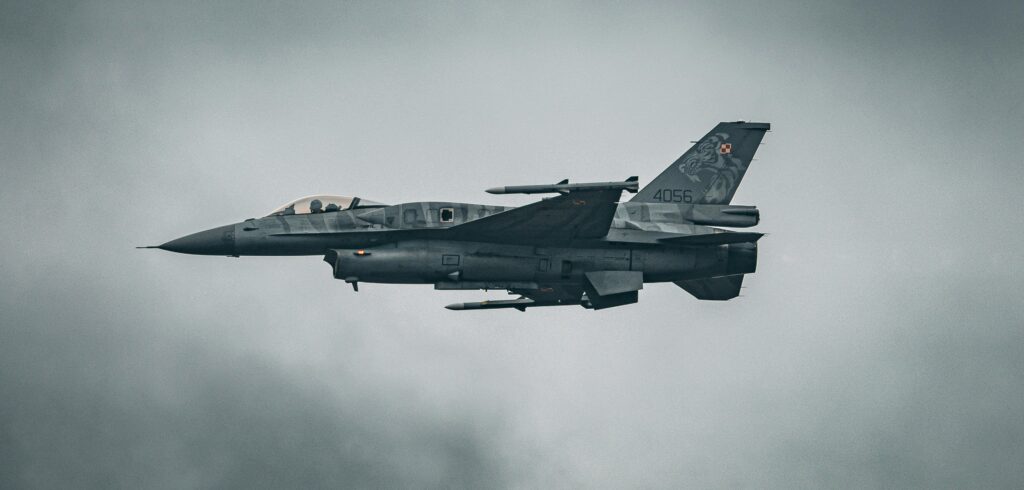 A dynamic capture of an F-16 fighter jet soaring through the sky over Hechtel-Eksel.